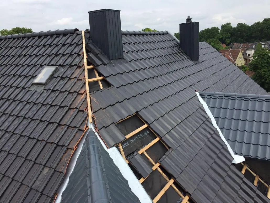 Dachsanierung mit schwarzen Tondachziegeln, neuer Kehle und blechverkleideten Schornsteinen