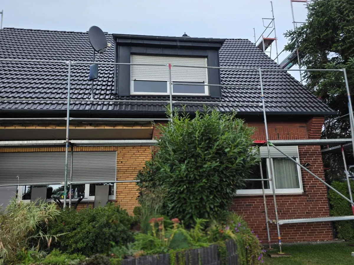 Dachsanierung an einem Wohnhaus mit anthrazitfarbenen Dachpfannen und blechverkleideter Gaube