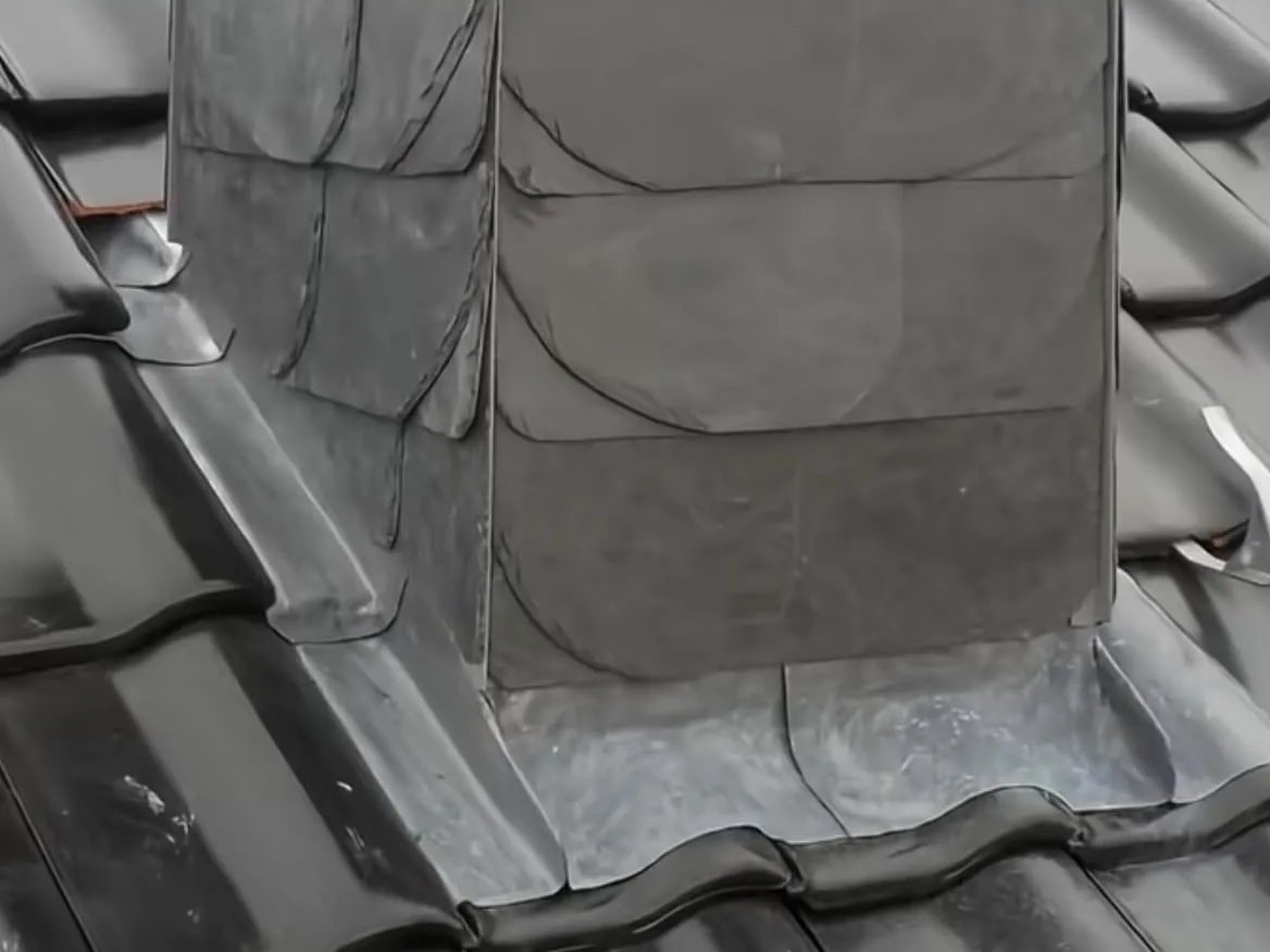 Schornsteinverkleidung aus Naturschiefer mit Metallanschluss an glasierte Tondachziegel